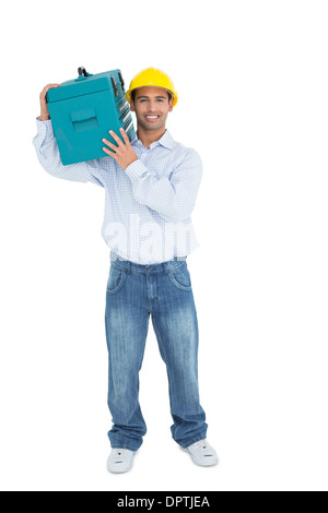 Smiling handyman in hard hat carrying a toolbox Stock Photo