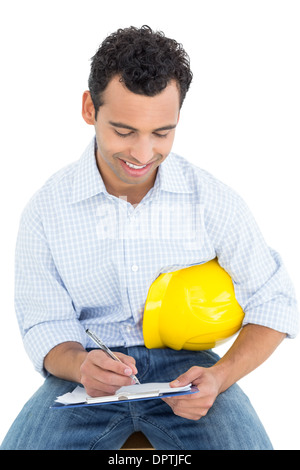 Handyman with yellow hard hat writing in clipboard Stock Photo