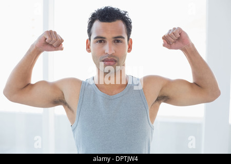 Fit young man flexing muscles in fitness studio Stock Photo