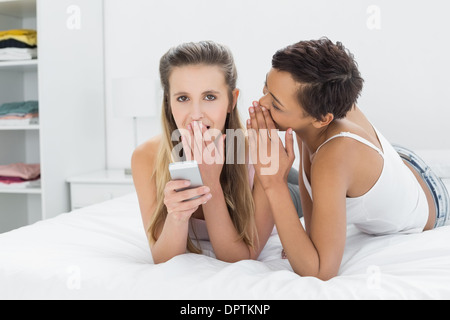 Two relaxed female friends gossiping in bed Stock Photo