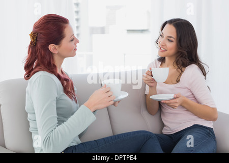 Young female friends chatting over coffee at home Stock Photo