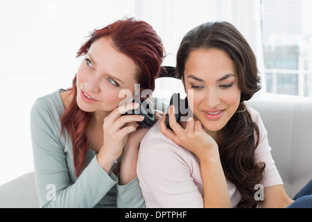 Friends listening music through headphones together at home Stock Photo