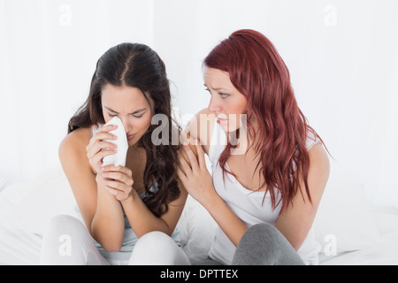 Woman consoling a crying female friend at home Stock Photo