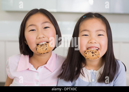 Portrait of two smiling young girls enjoying cookies Stock Photo