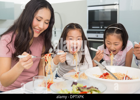 Woman with kids enjoying spaghetti lunch in kitchen Stock Photo