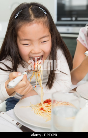 Happy young kid enjoying spaghetti lunch in kitchen Stock Photo