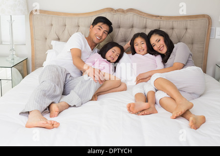 Full length of a happy family of four lying in bed Stock Photo