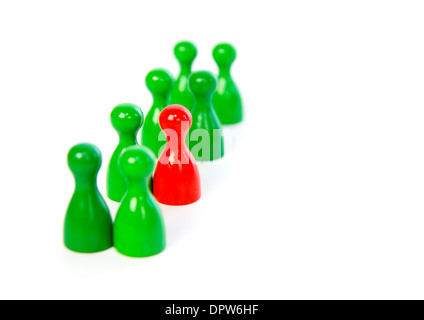 Red pawn in a line-up of green pawns against white background Stock Photo