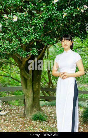 Young woman smiling in woodland park wearing traditional Vietnamese attire. Stock Photo