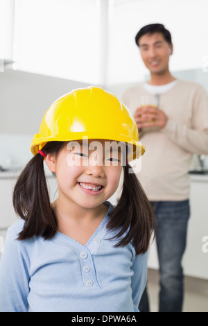 Cute girl in yellow hard hat with father in background Stock Photo