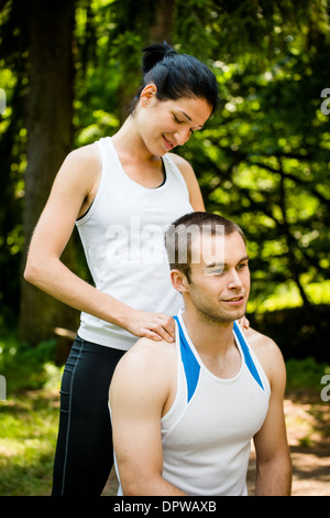 Young woman massaging her friend after sport training in nature Stock Photo