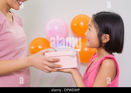 Woman giving gift box to a little girl at a birthday party Stock Photo