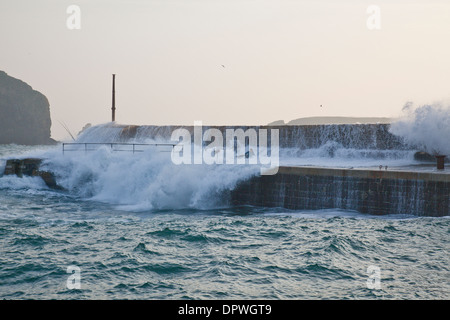 Mullion Cove harbour, Lizard Peninsula, Cornwall. People fishing on the harbour wall are being knocked over by huge waves Stock Photo