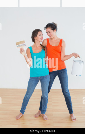Friends with paint brushes and cans in a new house Stock Photo