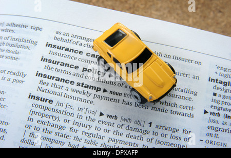 TOY CAR WITH DICTIONARY WITH INSURANCE WORD RE CAR INSURANCE POLICY POLICIES SCHEME RISING PRICES COSTS ACCIDENT DAMAGE PRICES Stock Photo