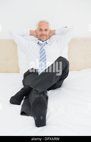 Portrait of a relaxed mature businessman sitting in bed Stock Photo