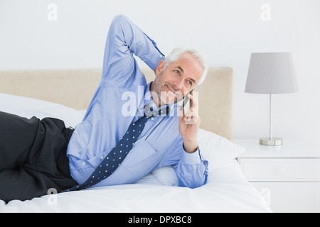 Mature businessman using mobile phone in bed Stock Photo