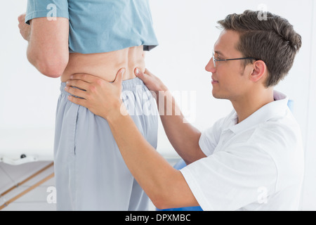 Male therapist massaging mans lower back in gym hospital Stock Photo