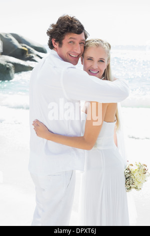 Smiling bride and groom looking at camera hugging Stock Photo