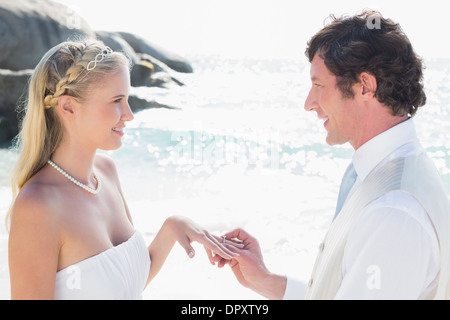 Man placing ring on pretty blonde brides finger Stock Photo