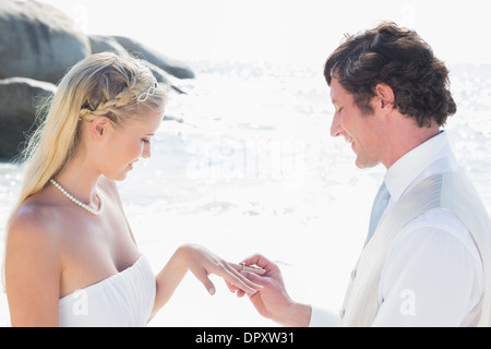 Man placing ring on happy brides finger Stock Photo