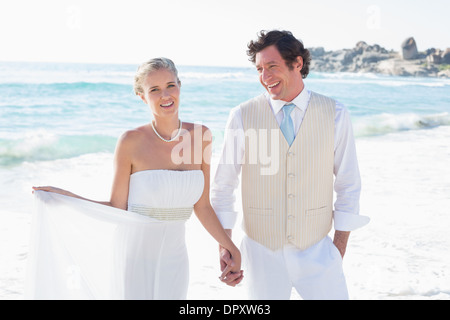 Newlyweds walking hand in hand and smiling Stock Photo