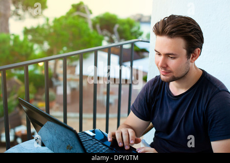 Young man working on laptop with outdoors view. Stock Photo