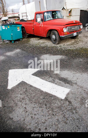 Dec 29, 2008 - Port Townsend, Washington, USA - In the shipyard in Port Wownsend, WA., old cars line the streets everywhere, including this old truck down an alley way next to a blue trash dumbster with a white painted traffic arrow painted onto the asphalt on the ground. (Credit Image: © Steven Karl Metzer/ZUMA Press) Stock Photo