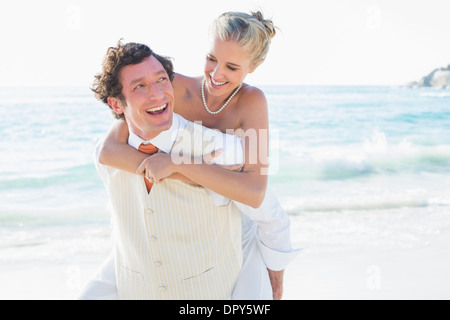 Smiling bride getting a piggy back from new husband Stock Photo