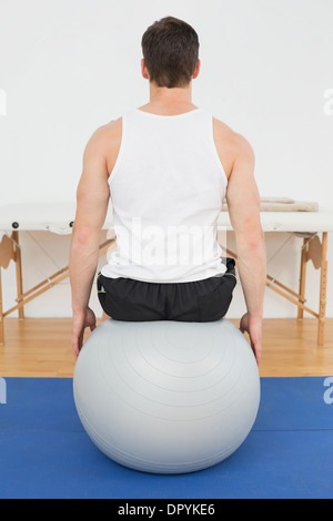 Rear view of a young man sitting on yoga ball Stock Photo