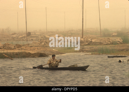 Iran Iraq war also known as First Persian Gulf War or Gulf War. 1984 Soldier recovering from recent battle in canoe amongst the devastation of war. The Mesopotamian marshes, a sandstorm in the air. Near Basra Southern Iraq. 1980s HOMER SYKES Stock Photo