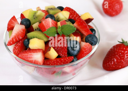 Fruit salad in a glass bowl with strawberries, blueberries and peaches Stock Photo