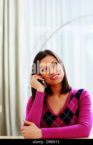 Middle-aged smiling woman talking on the phone and looking away Stock Photo