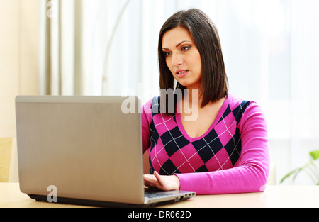 Middle-aged thoughtful woman using laptop at home Stock Photo
