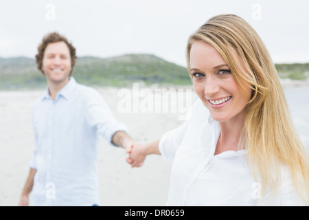 Smiling casual couple holding hands at beach Stock Photo