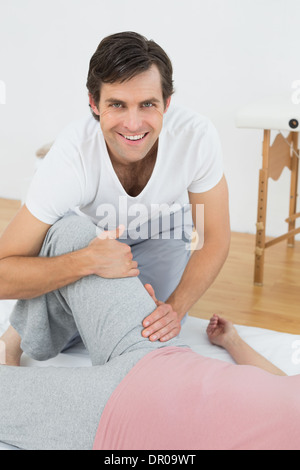Portrait of a smiling physical therapist examining woman's leg Stock Photo