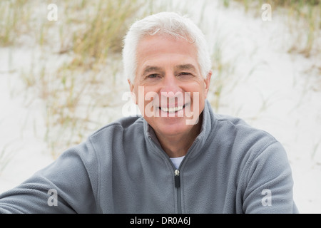 Smiling casual senior man relaxing at beach Stock Photo