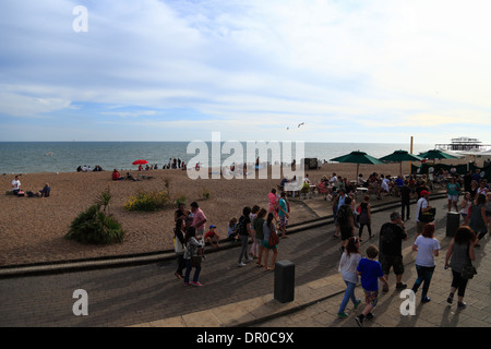 People walk along the beachfront promenade in Brighton city, East Sussex, United Kingdom, during an early summer evening. Stock Photo