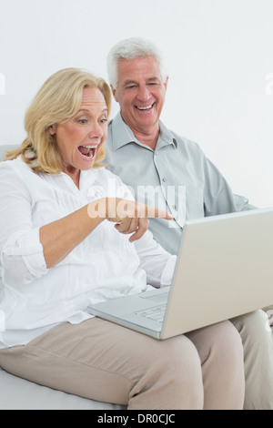 Cheerful senior couple using laptop at house Stock Photo
