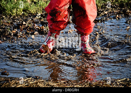 Child in wellington boots splashing in a puddle Stock Photo