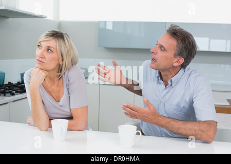 Couple with coffee cups having a fight in kitchen Stock Photo