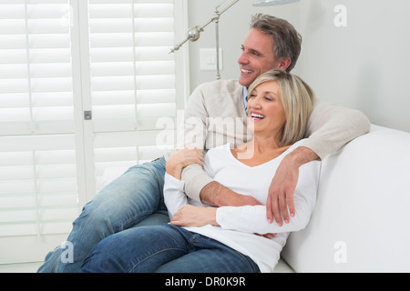 Happy couple embracing while sitting on sofa Stock Photo