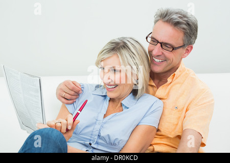 Happy couple doing the newspaper crossword puzzle at home Stock Photo