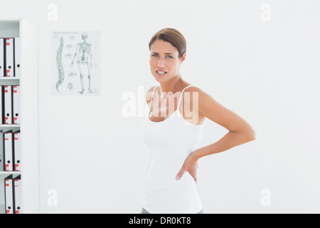 Beautiful young woman with back pain in medical office Stock Photo