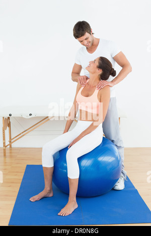 Woman on yoga ball working with physical therapist Stock Photo