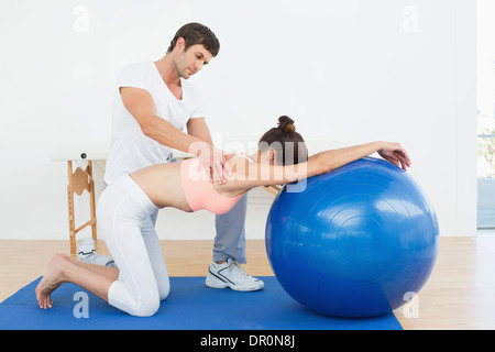 Physical therapist assisting woman with yoga ball Stock Photo