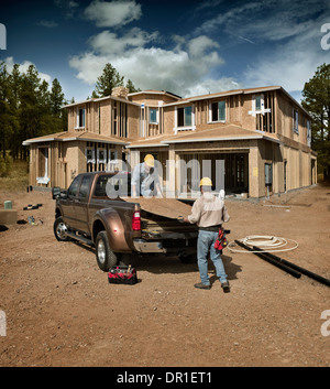 Construction workers carrying plywood on site Stock Photo