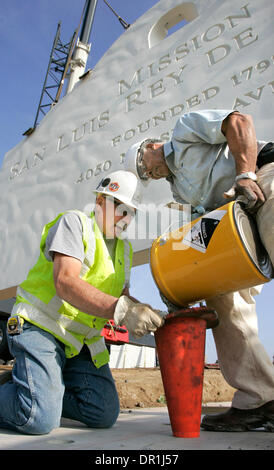 December 4, 2008, Oceanside, California, USA GEORGE SCHULTZ, left and ALEX JOHNSON, at right, pour a special anchor bolt grout into holes drilled into the base of the Mission San Luis Rey's new 12 foot tall concrete sign. Steel coil rods installed vertically into the base of the sign section suspended behind them will go into the holes when the section is placed on to the base Cred Stock Photo