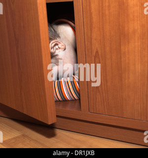 Scared child boy hiding in wardrobe Stock Photo