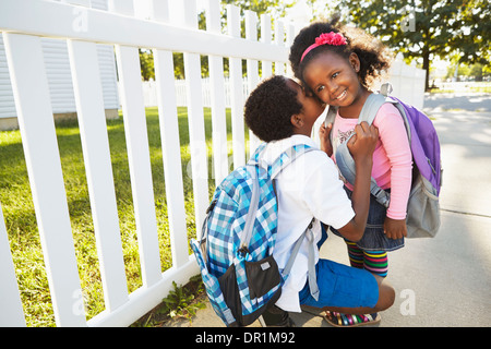 Mixed race boy whispering in sister's ear Stock Photo